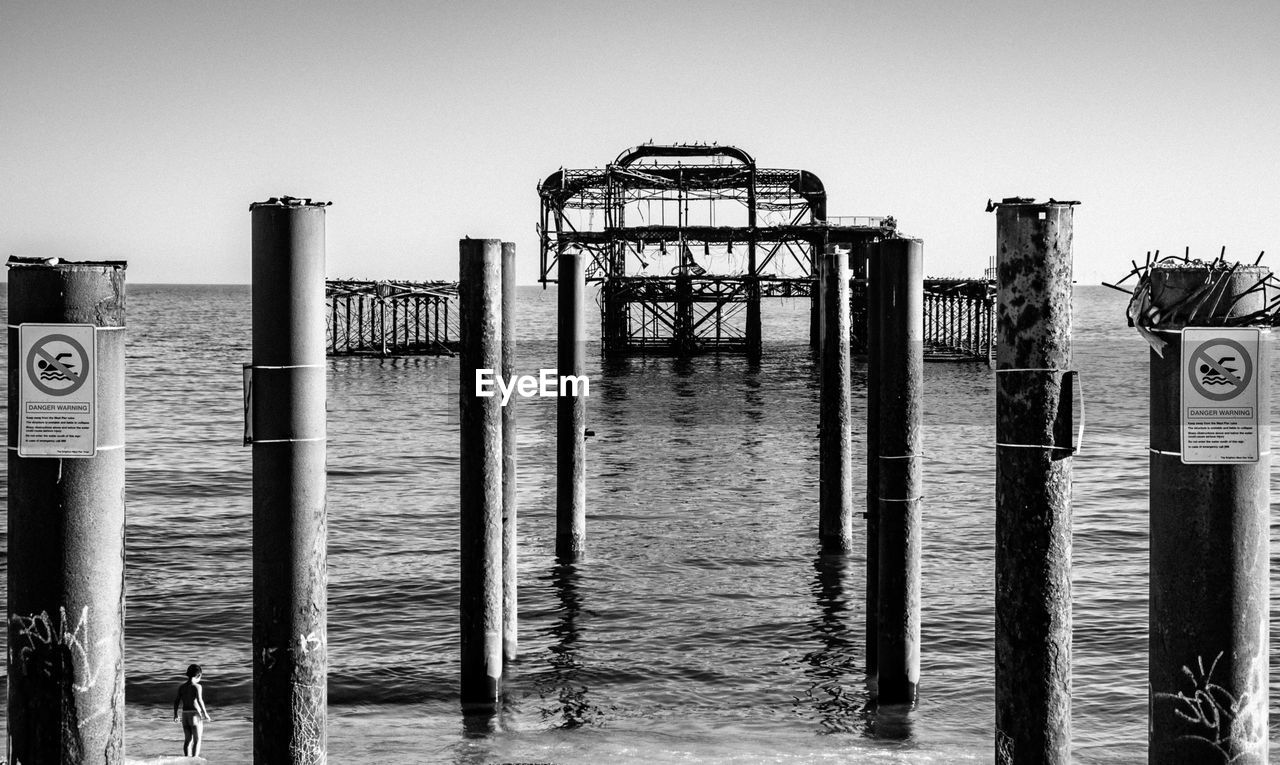 WOODEN POSTS ON PIER AGAINST SKY