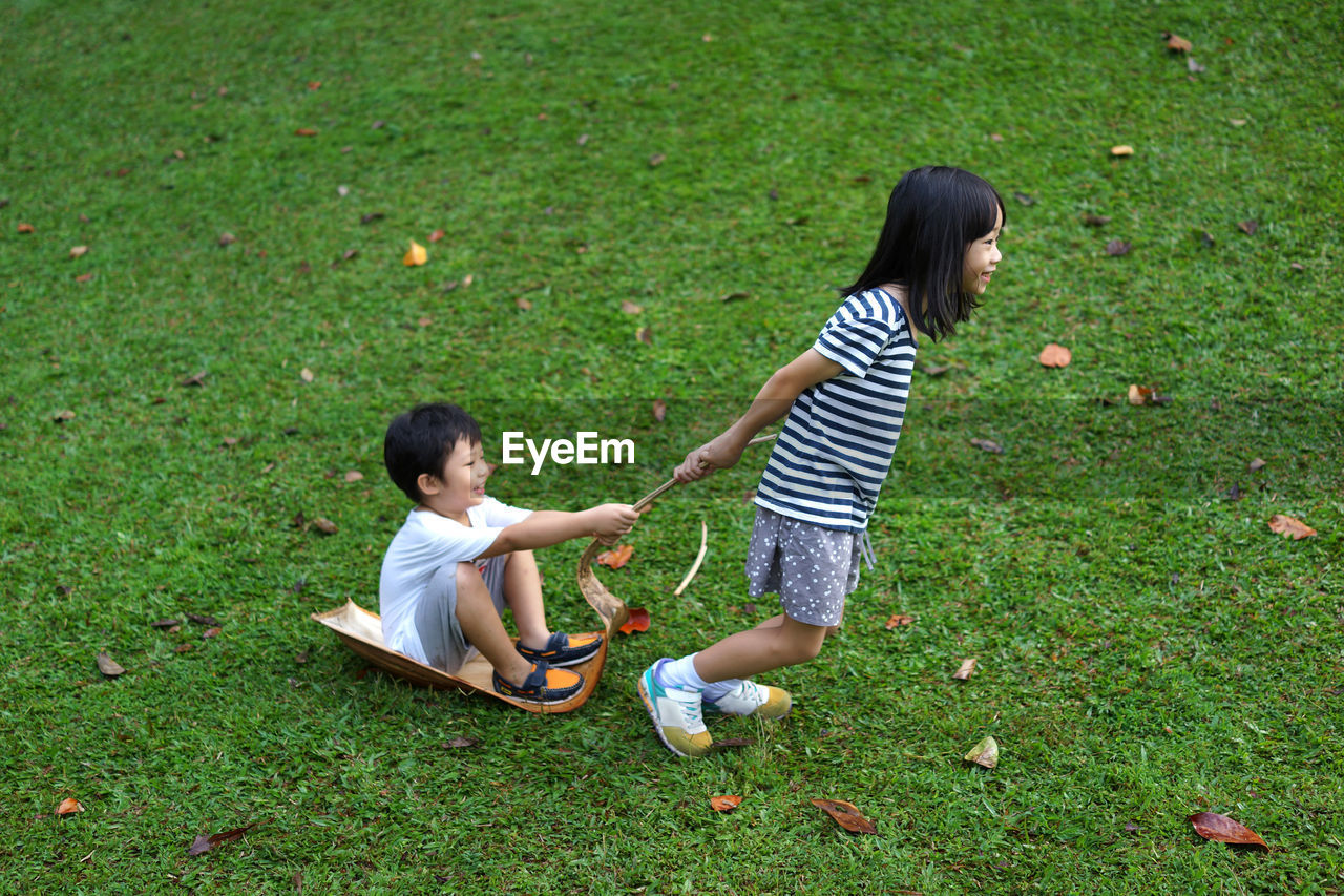 High angle view of siblings playing on grassy field at park