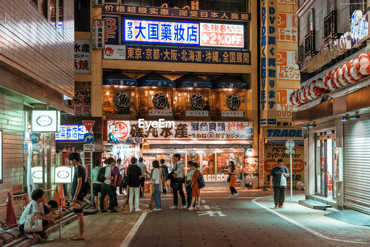 GROUP OF PEOPLE WALKING ON CITY STREET AT STORE