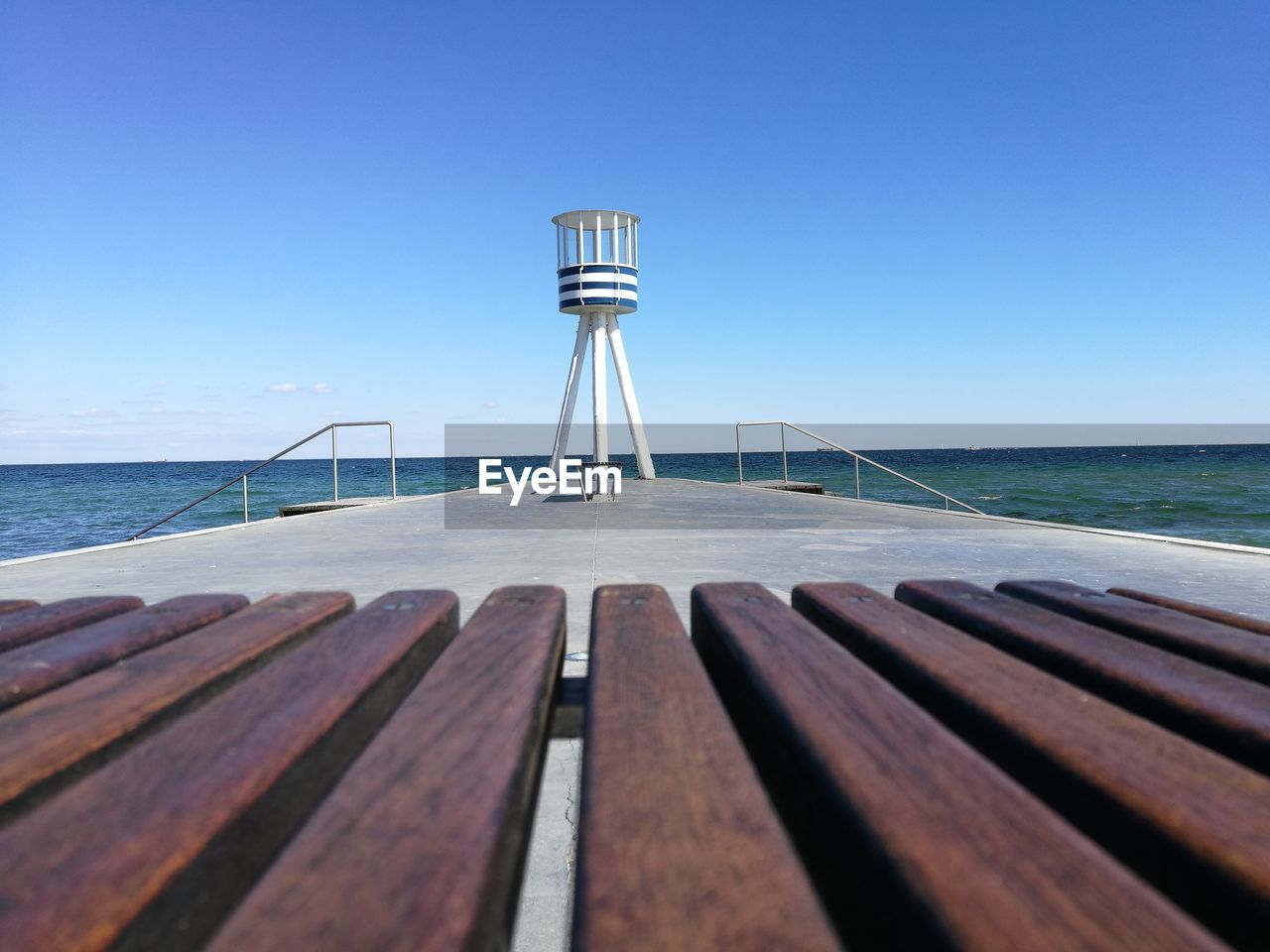 Pier over sea against clear blue sky