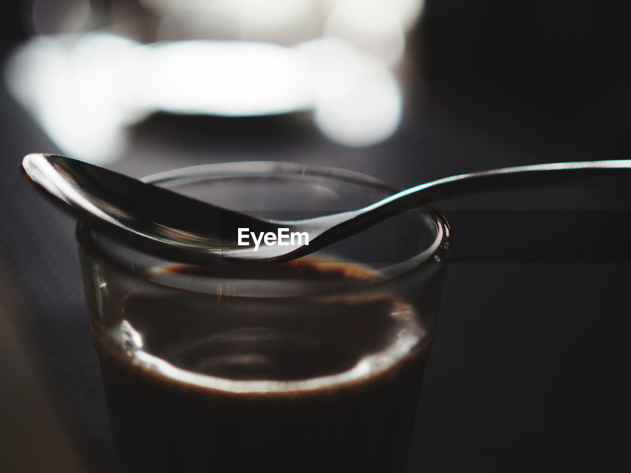 Contrast of silver spoon on top of a glass of coffee
