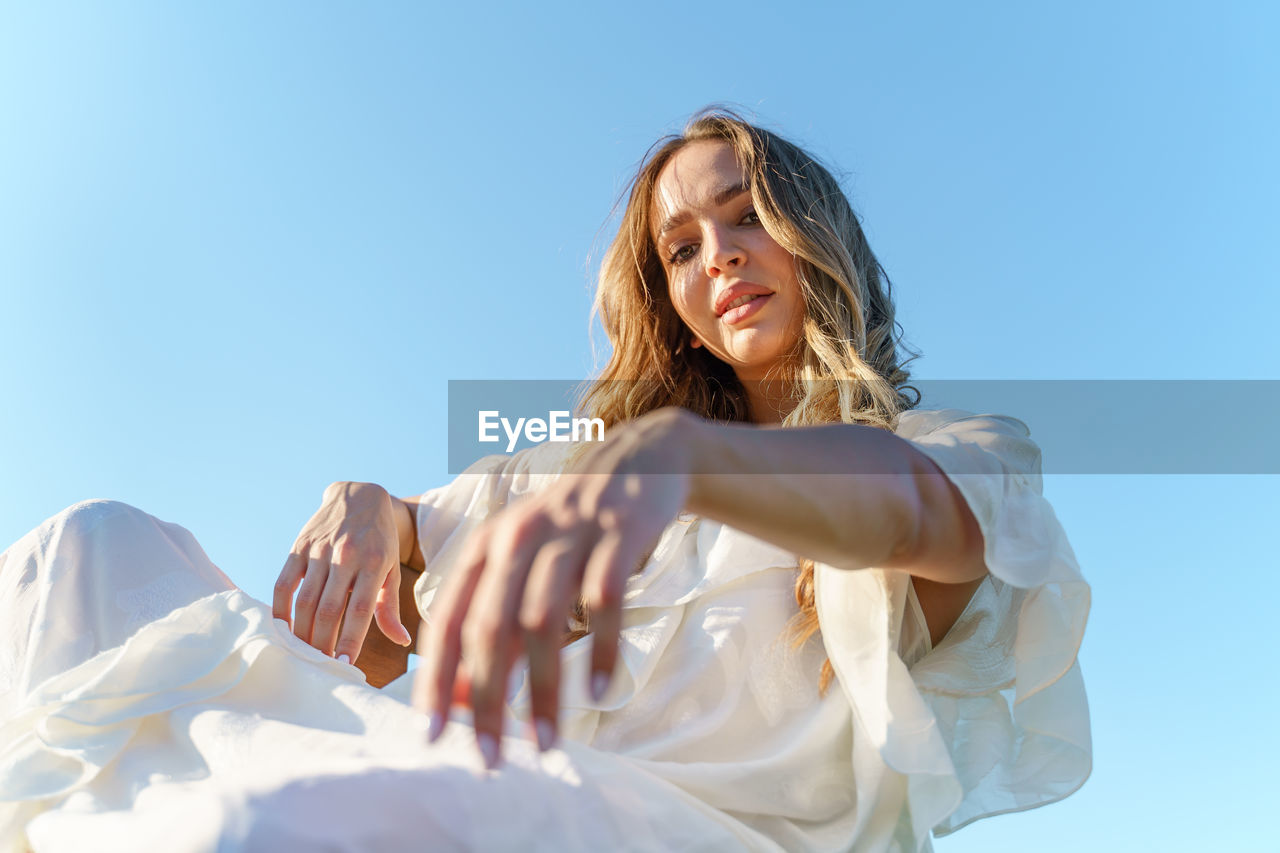 WOMAN SMILING AGAINST BLUE SKY