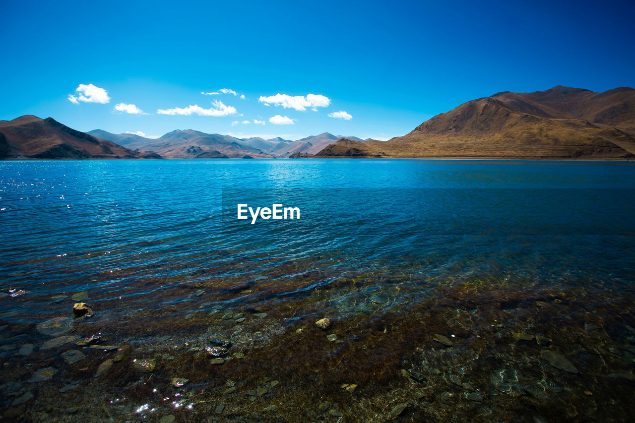 SCENIC VIEW OF LAKE BY MOUNTAINS AGAINST BLUE SKY