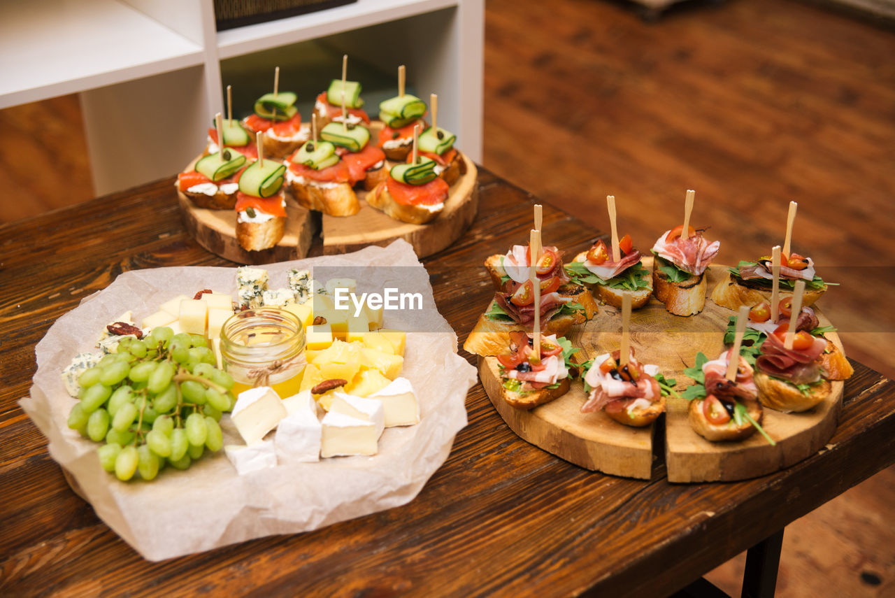 Table of cold cuts and appetizers. cheese slices with grapes, tapas with salmon filet and cucumber