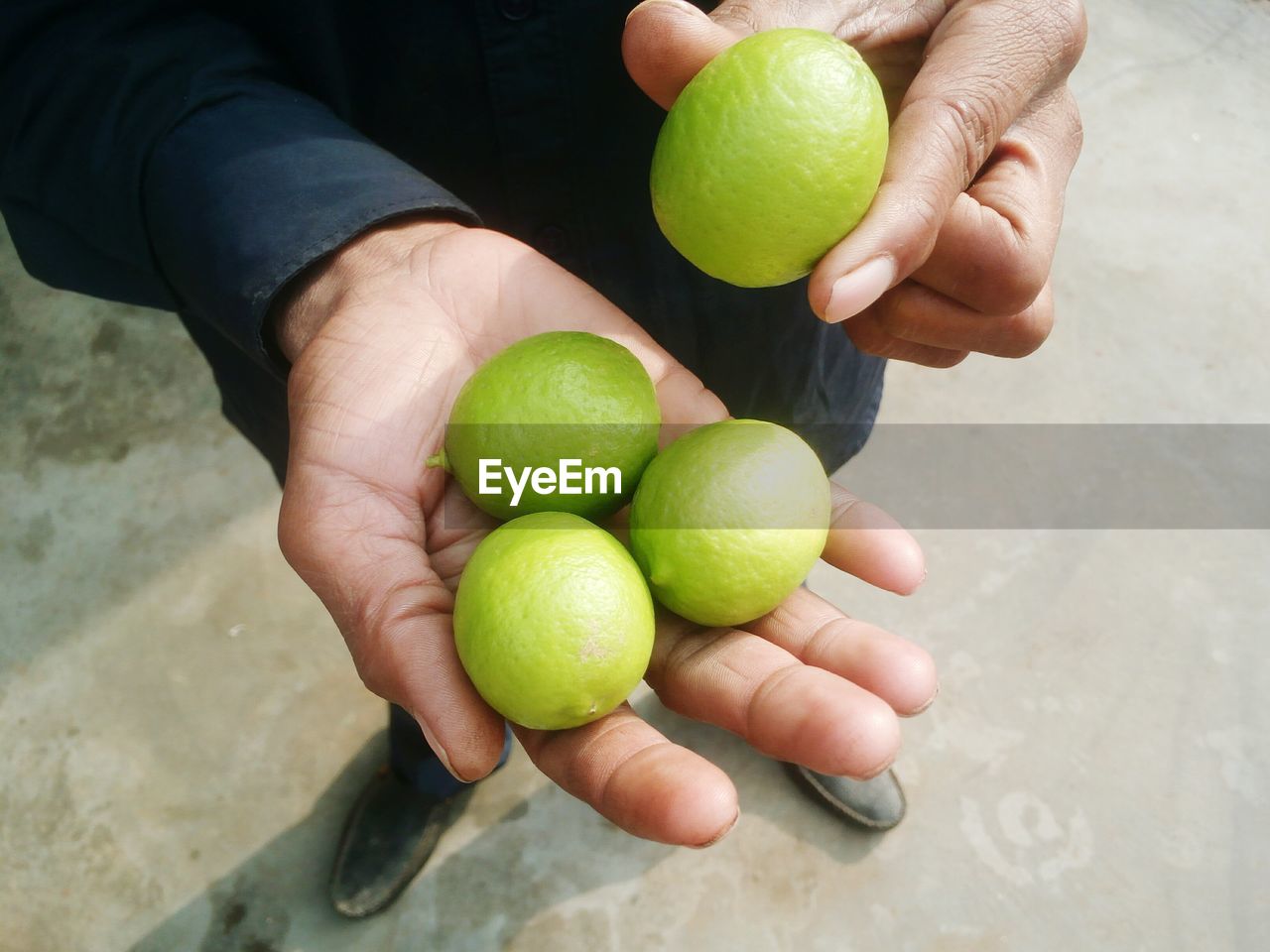 Low section of man holding lemons on footpath