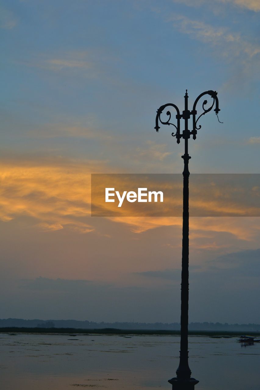 SILHOUETTE WOODEN POST ON SEA AGAINST SKY DURING SUNSET