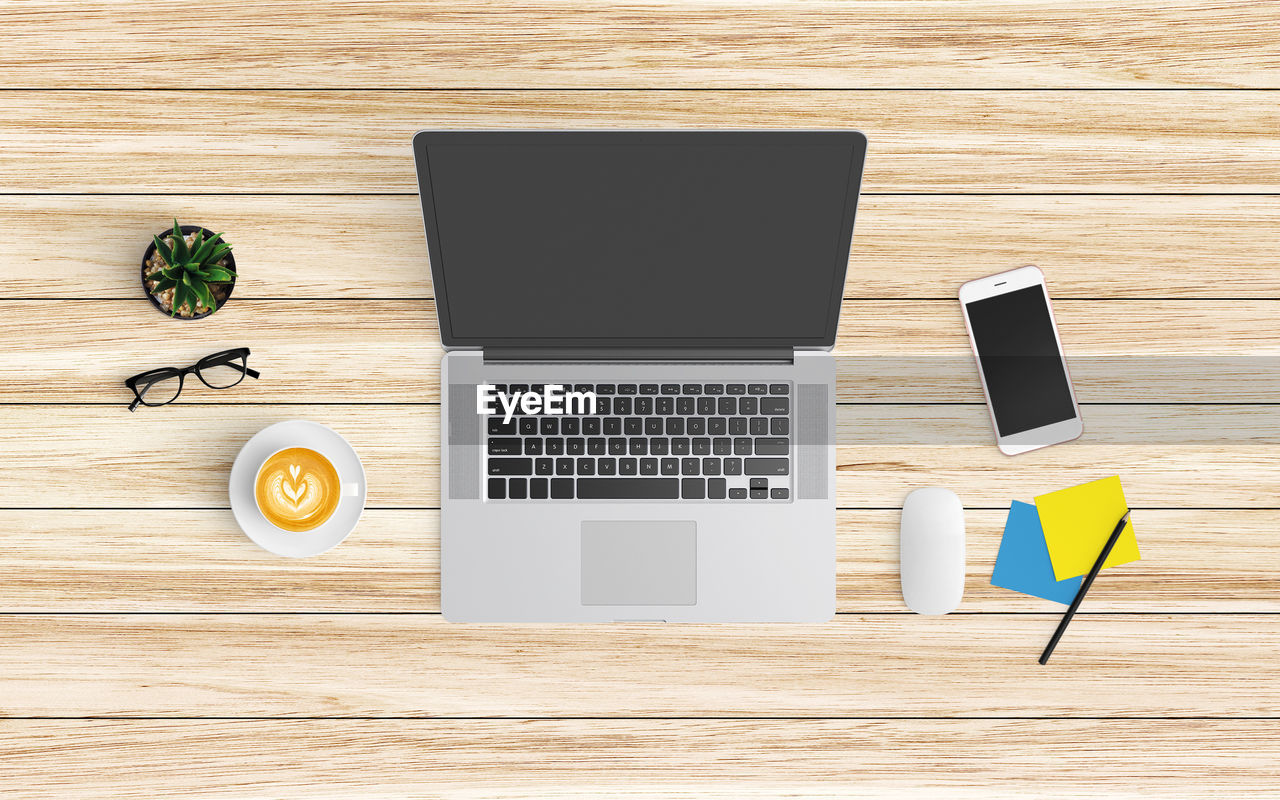 High angle view of technology with coffee and office supplies on wooden table