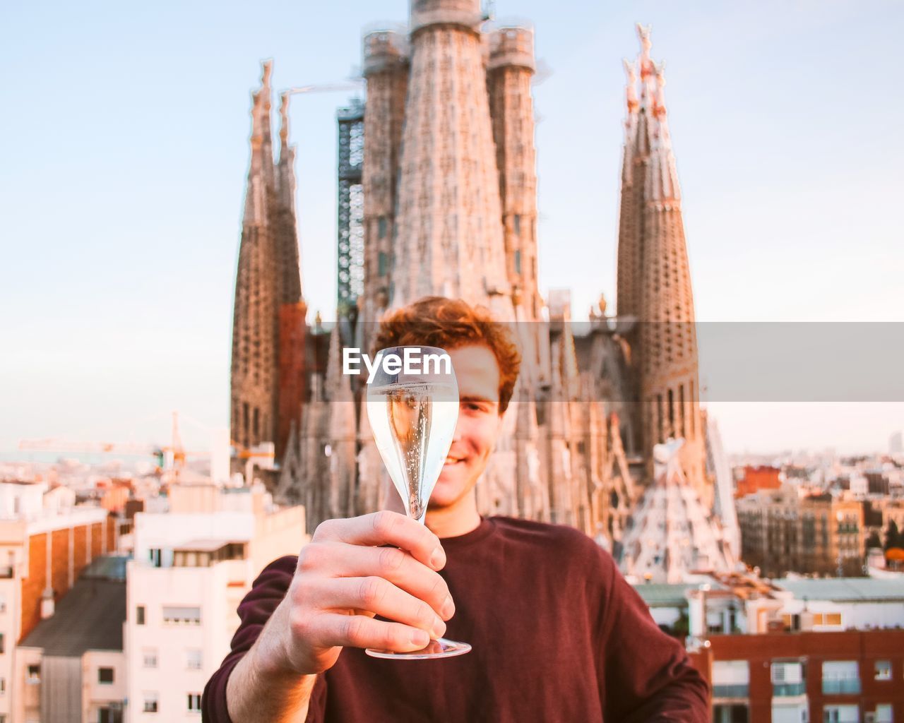 Man holding up a glass of champagne in front of sagrada familia