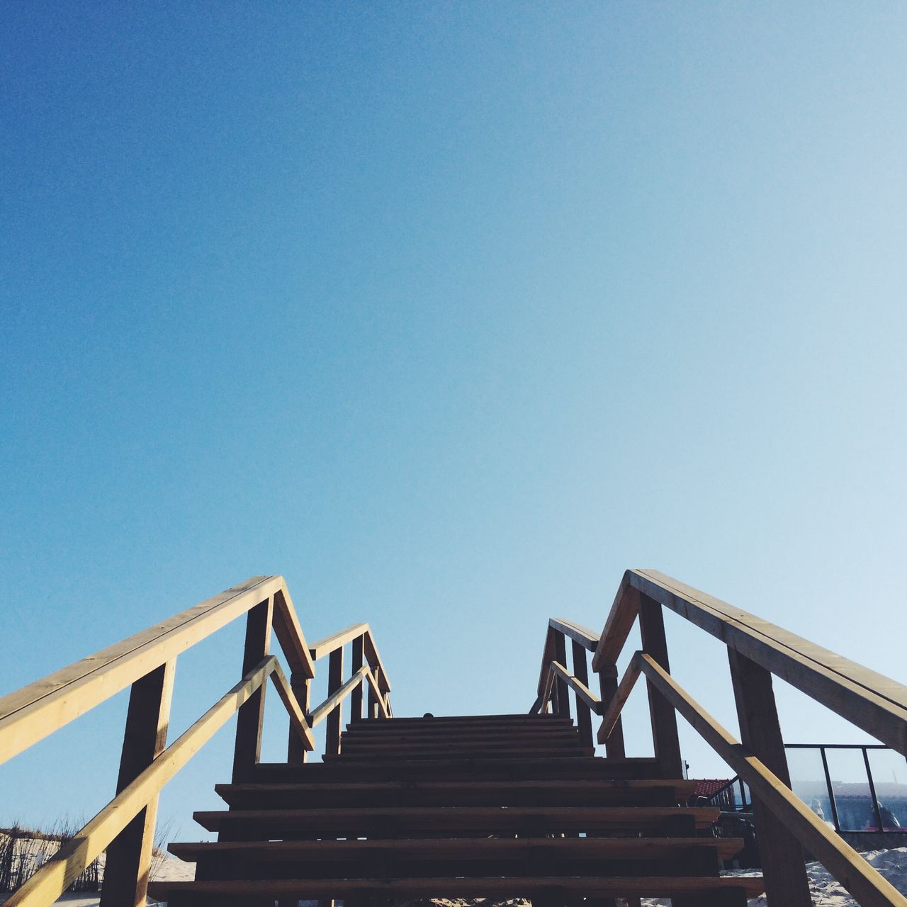 Low angle view of staircase at beach against clear blue sky