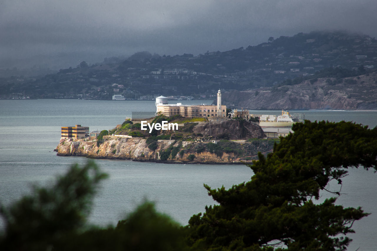 Scenic view of sea by city against mountains