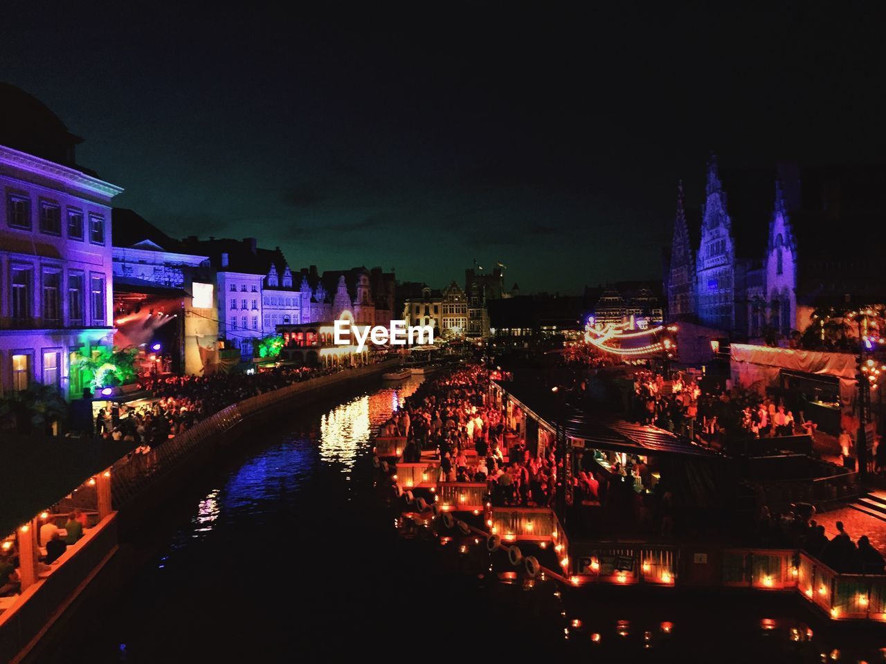 Canal amidst illuminated buildings in town