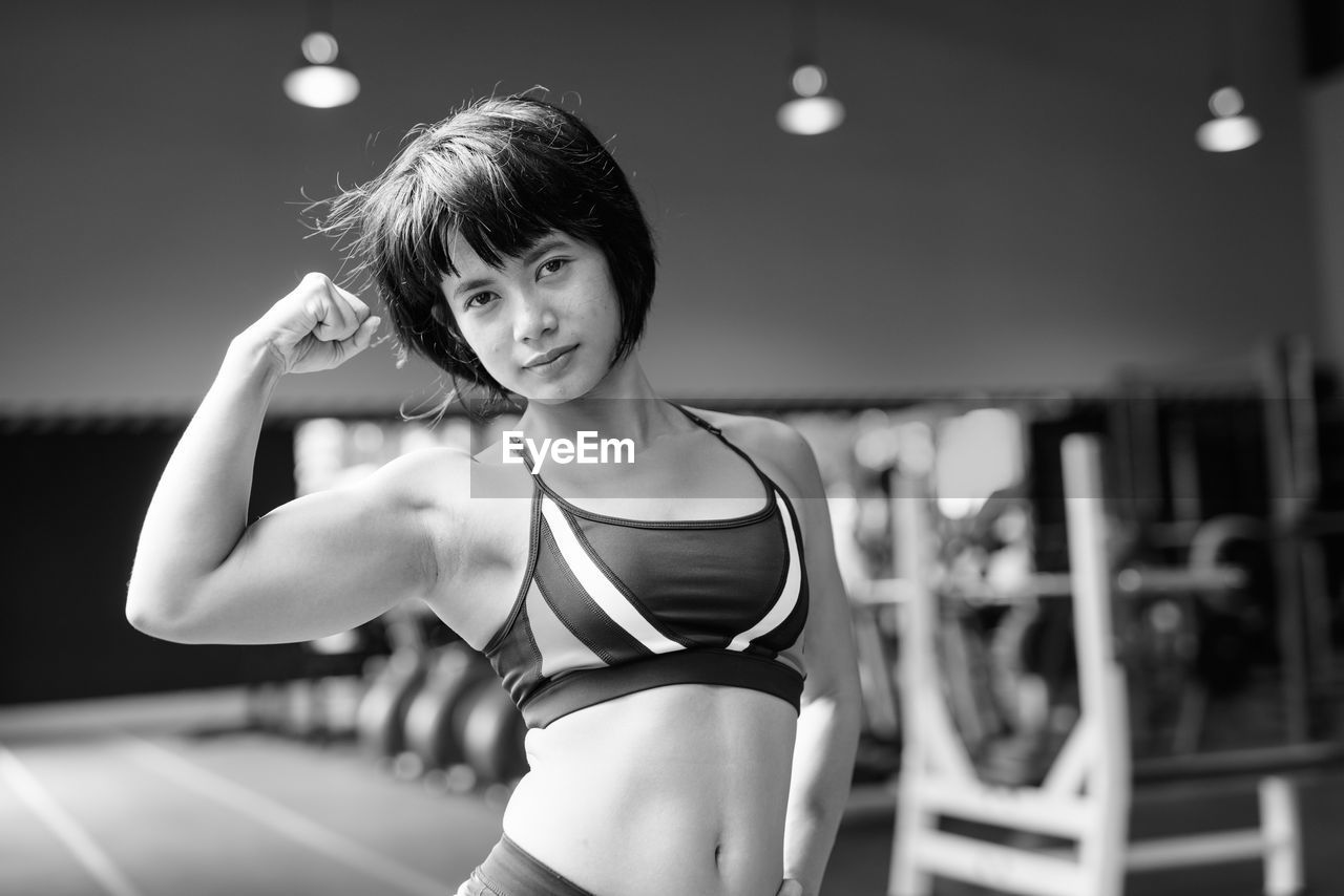 Portrait of young woman standing against blurred background