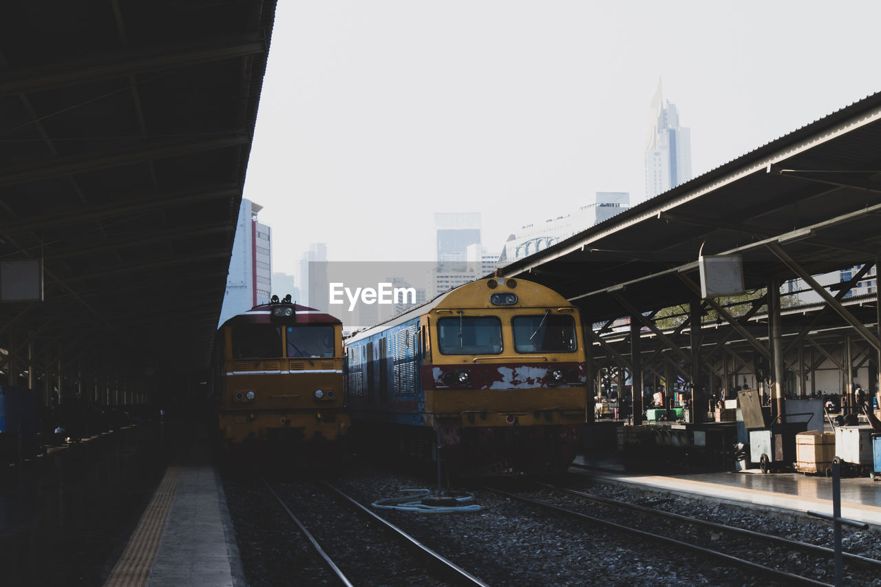 Train at railroad station in city against sky
