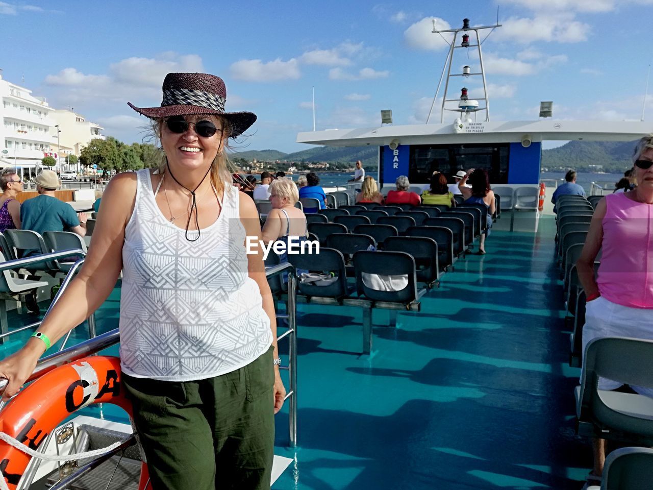 PORTRAIT OF HAPPY WOMAN STANDING AGAINST BOAT