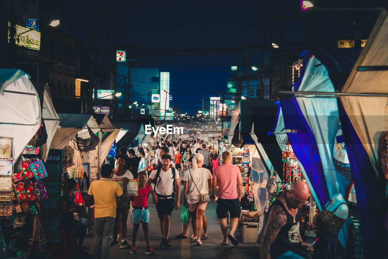 Group of people shopping in city market on street at night