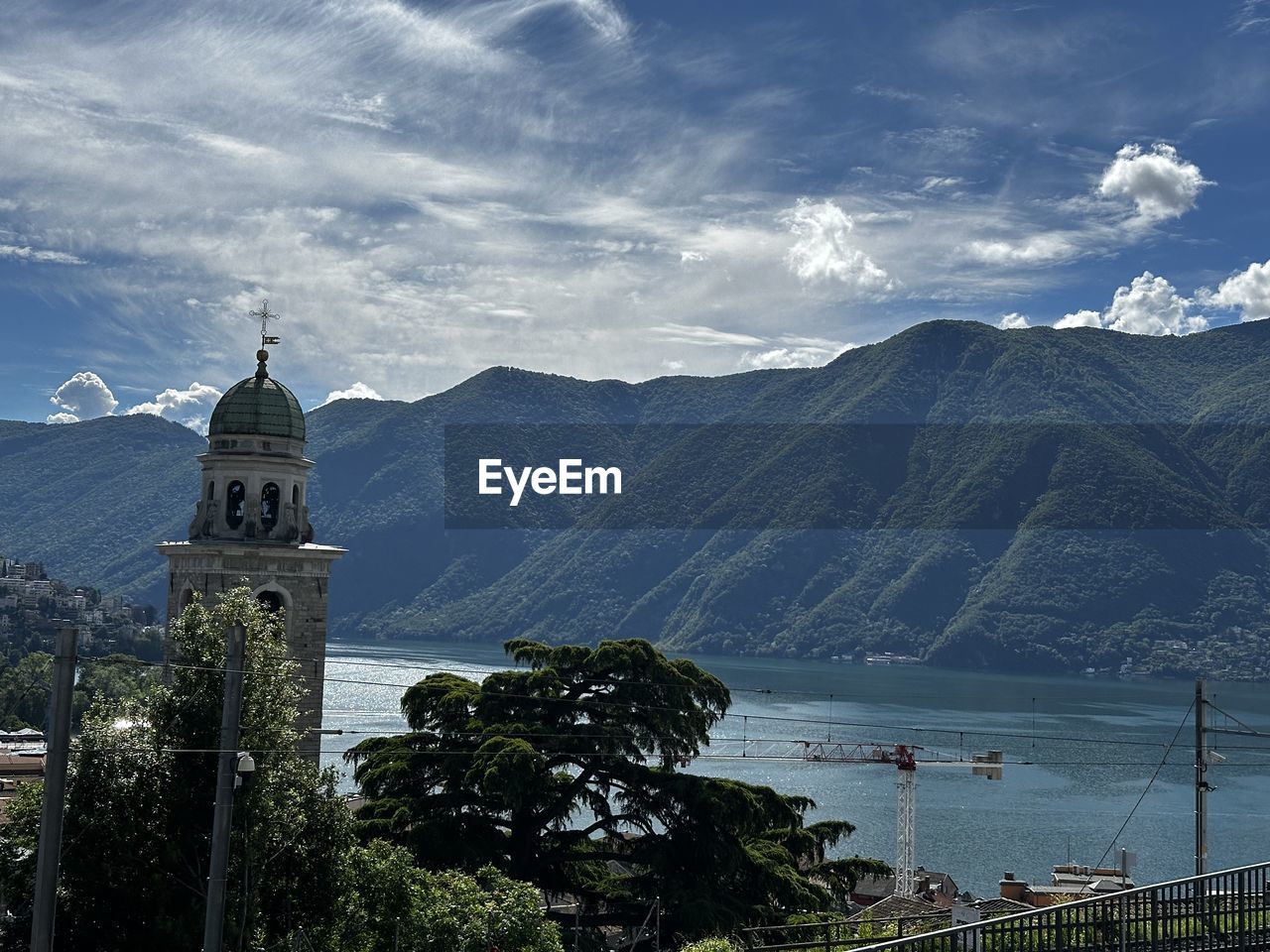 mountain, sky, architecture, travel destinations, water, built structure, nature, religion, cloud, building exterior, building, mountain range, scenics - nature, travel, place of worship, belief, tree, plant, environment, landscape, beauty in nature, tower, tourism, spirituality, landmark, history, no people, the past, land, outdoors, lake, city, blue, day, holiday, catholicism, vacation, trip