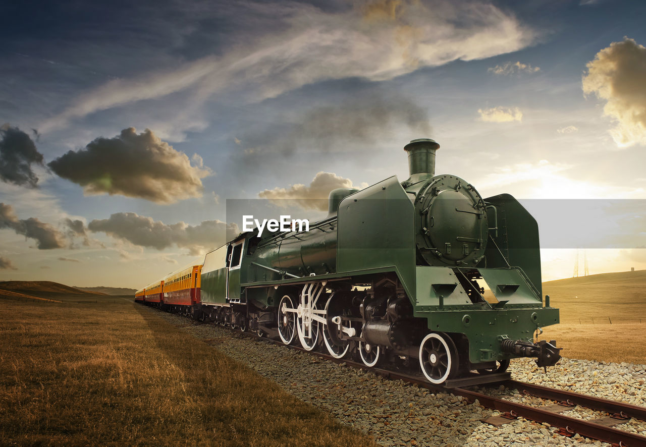 Train on railroad tracks against sky during sunset