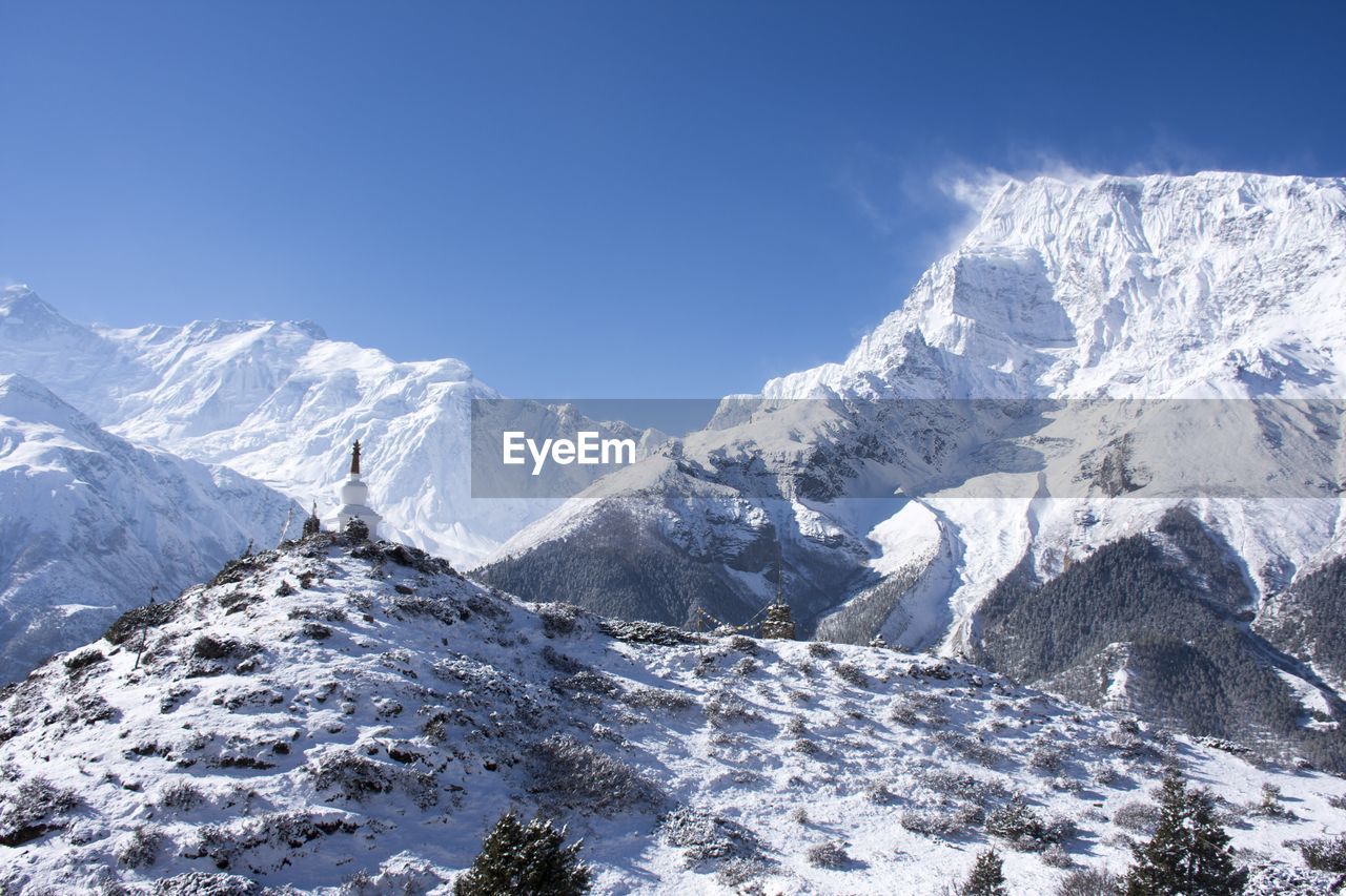 Scenic view of snowcapped mountains against blue sky