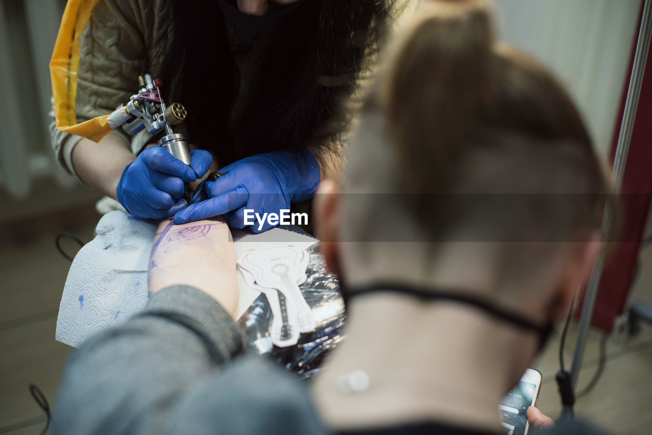 Artist tattooing on hand at studio