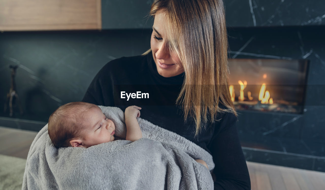 Mother carrying cute daughter while sitting at home