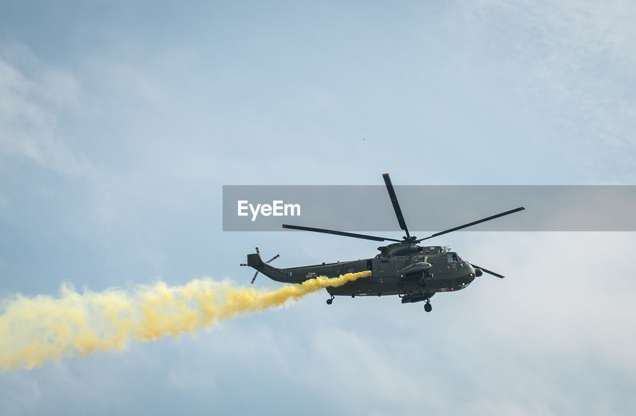 Low angle view of helicopter flying against sky