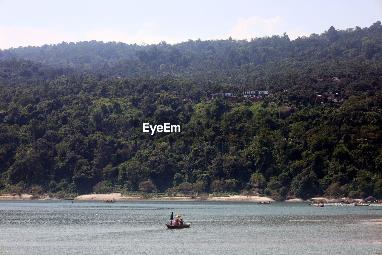 water, tree, river, plant, transportation, nature, nautical vessel, shore, land, vehicle, travel, mode of transportation, scenics - nature, bay, forest, environment, beauty in nature, reservoir, mountain, beach, boat, sky, body of water, holiday, day, coast, landscape, boating, vacation, outdoors, tourism, trip, travel destinations, leisure activity, tranquility, men, two people, lifestyles, adult, non-urban scene, tourist, watercraft