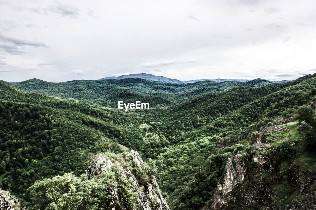 SCENIC VIEW OF VALLEY AND MOUNTAIN AGAINST SKY