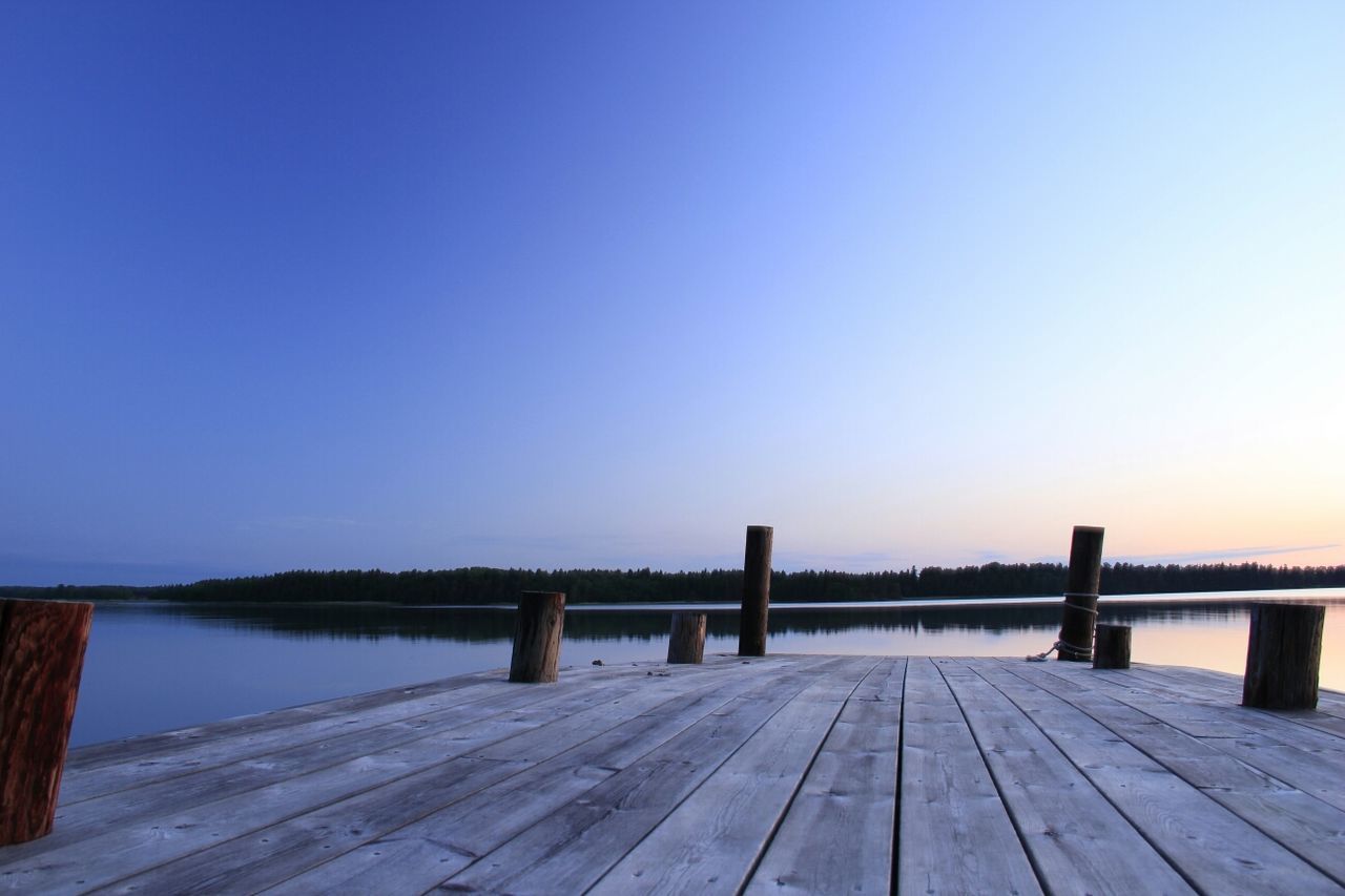 Pier over calm lake against clear sky