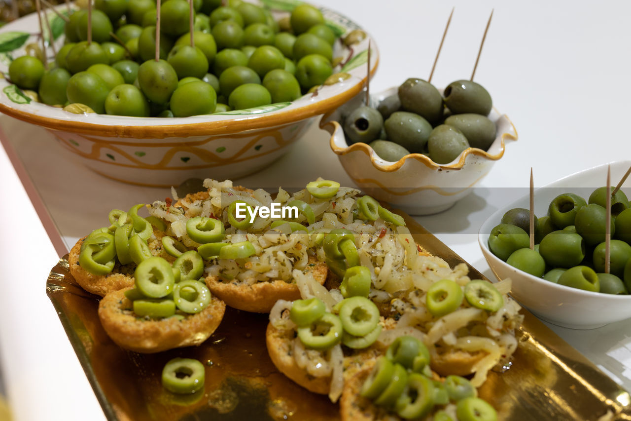 Appetizer of small pieces of toasted bread with olives and oregano.