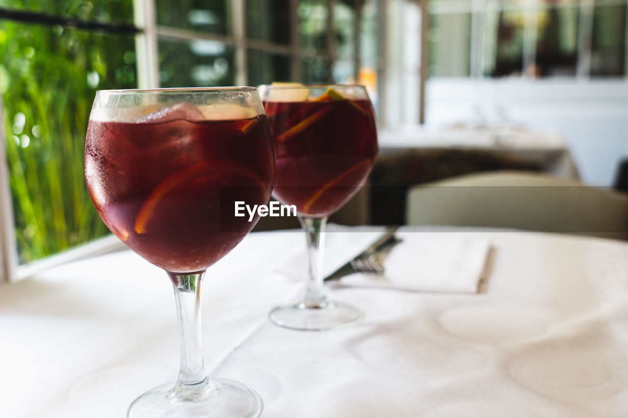 Two sangria wine glasses with slices of oranges against blurry background in a restaurant