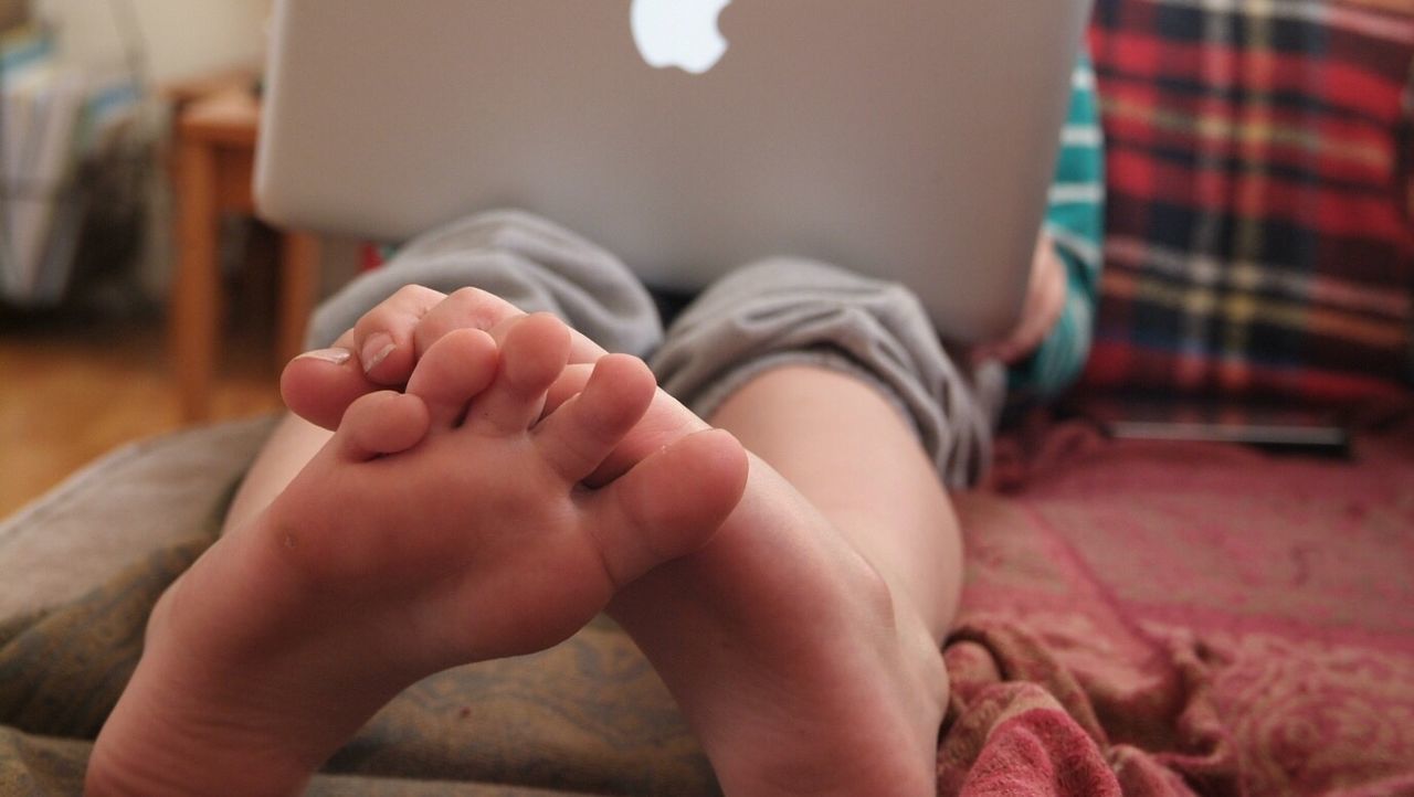 LOW SECTION OF BABY GIRL SITTING ON BED