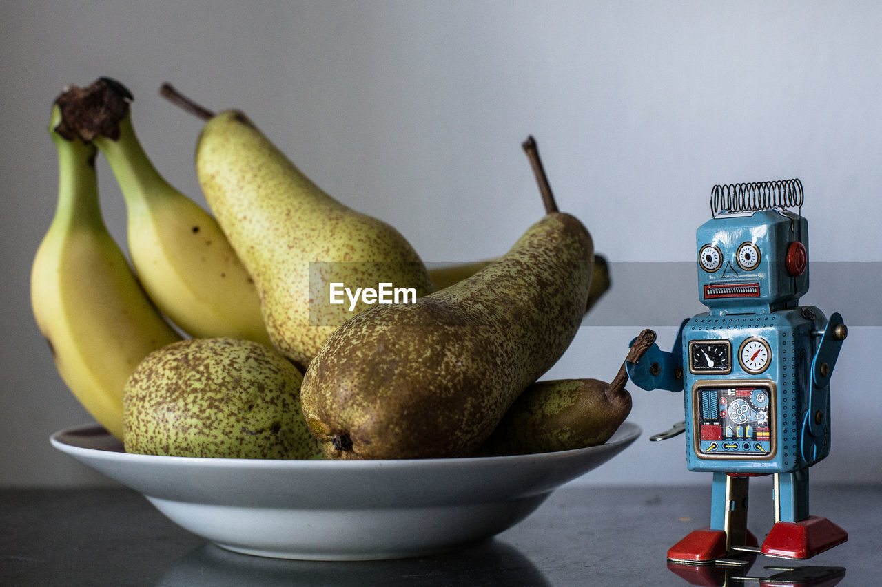 Close-up of robot  on table near a plate of fresh fruits