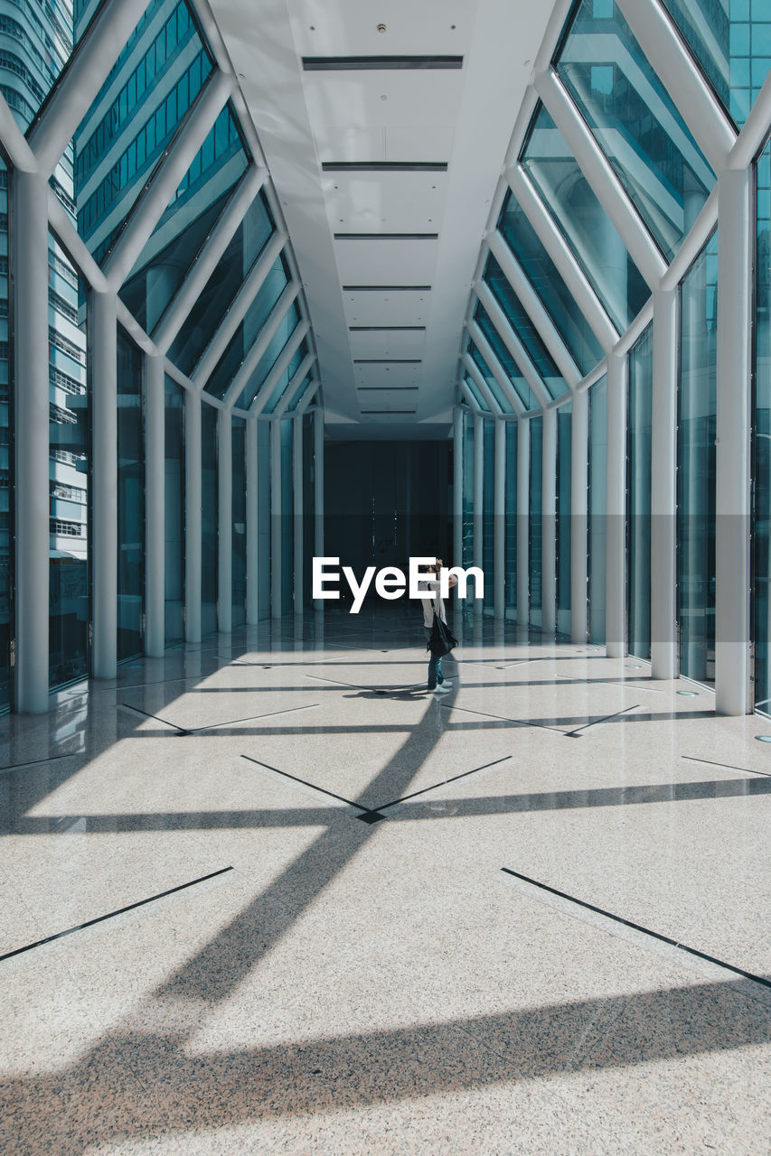 MAN WALKING IN CORRIDOR OF BUILDING