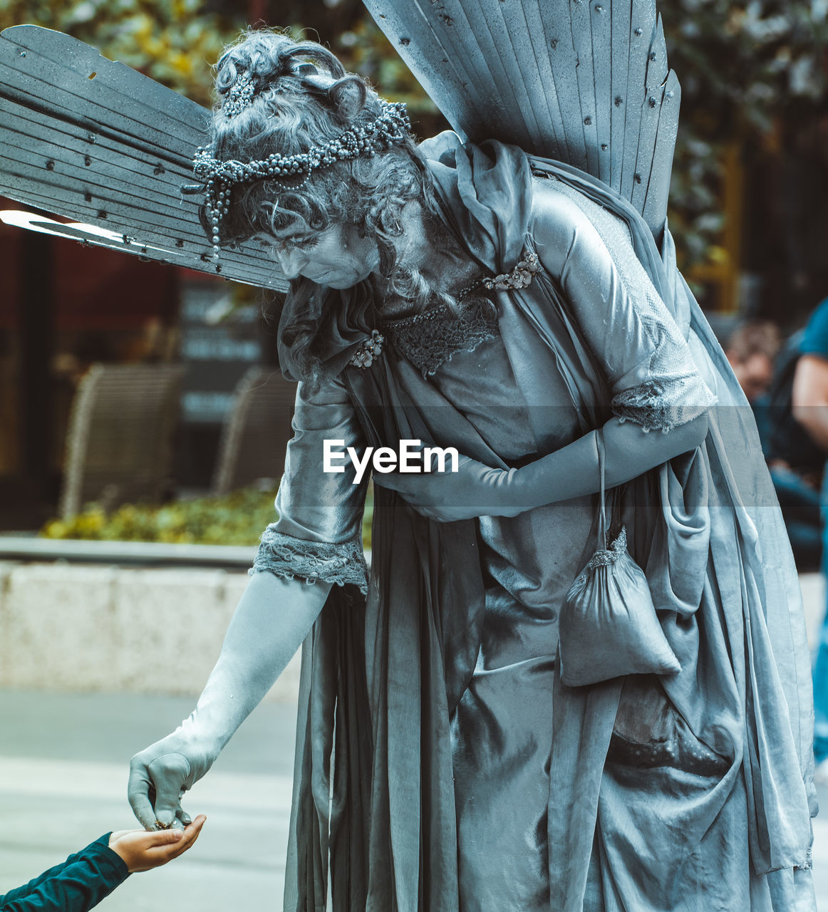 MIDSECTION OF MAN HOLDING STATUE AGAINST BLURRED BACKGROUND