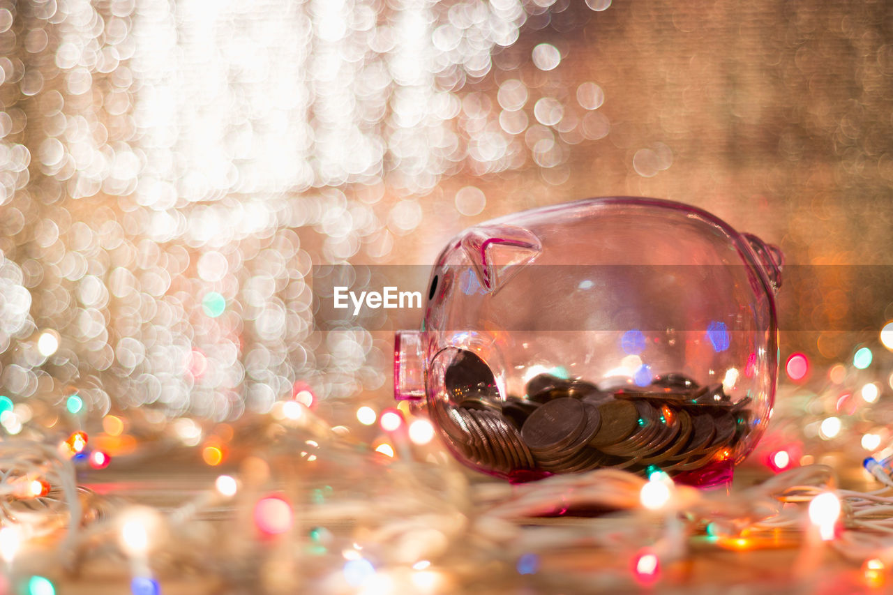 Close-up of coins in piggy bank amidst illuminated lights