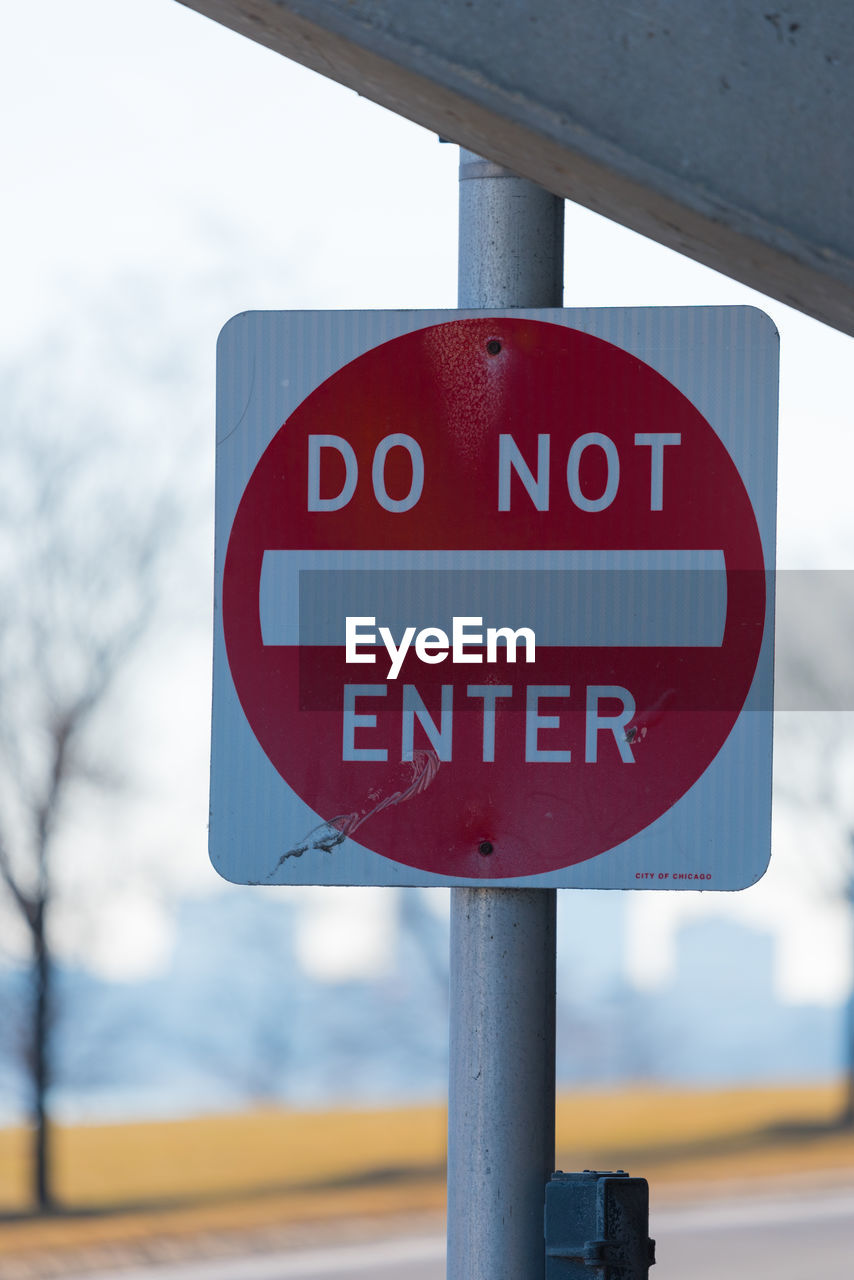 Close-up of do not enter sign against sky