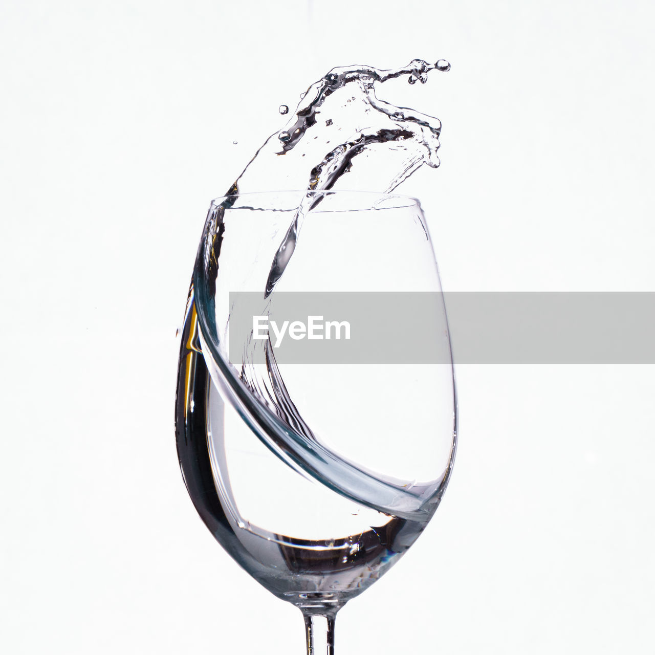 Close-up of water spilling from wineglass against white background
