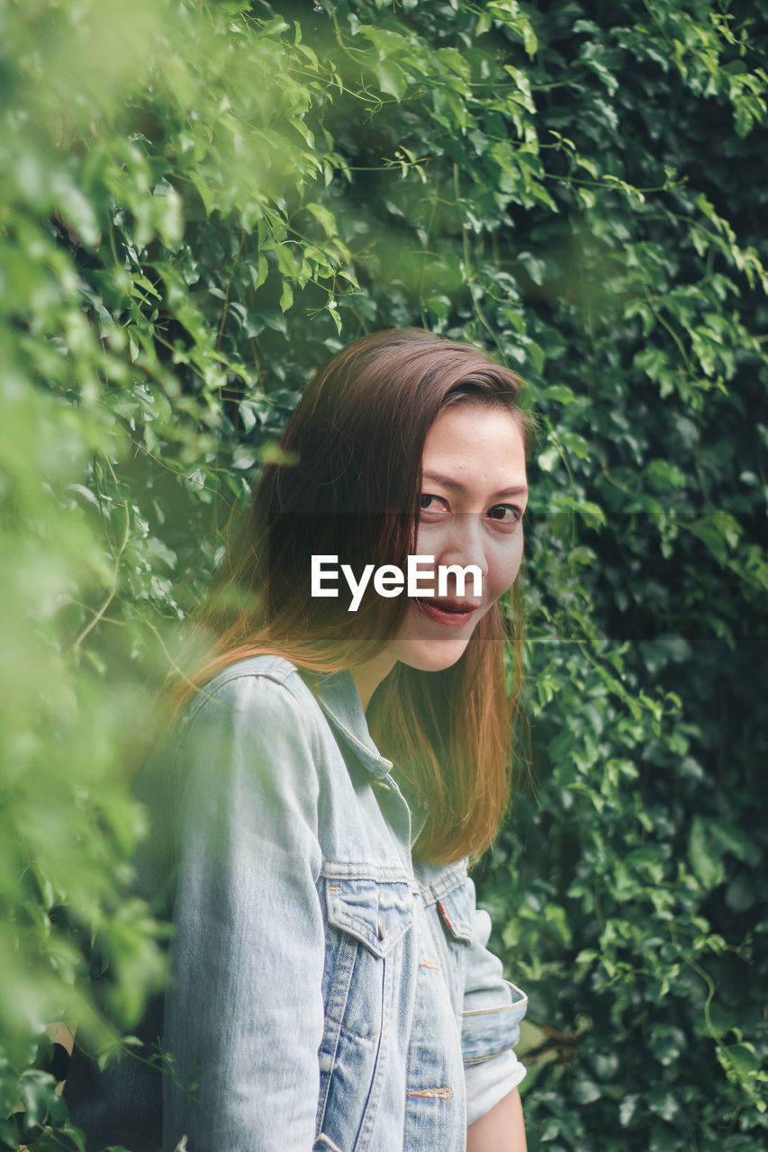 Portrait of beautiful woman standing by plants