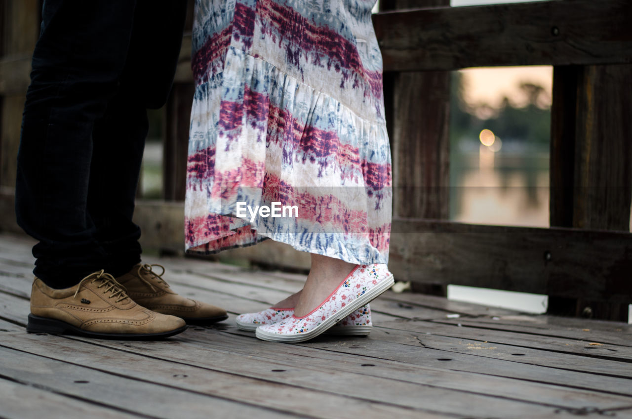 Low angle view of couple standing on wooden pier