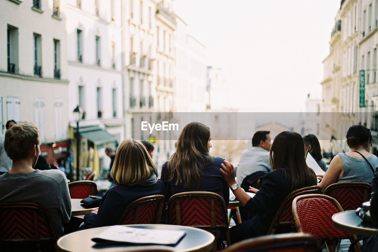 Rear view of people sitting at outdoor cafe in city