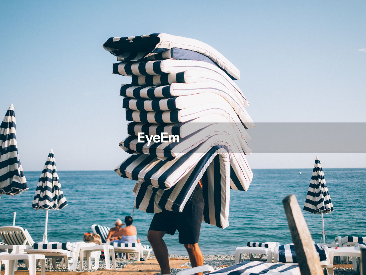 Person carrying cushions on beach