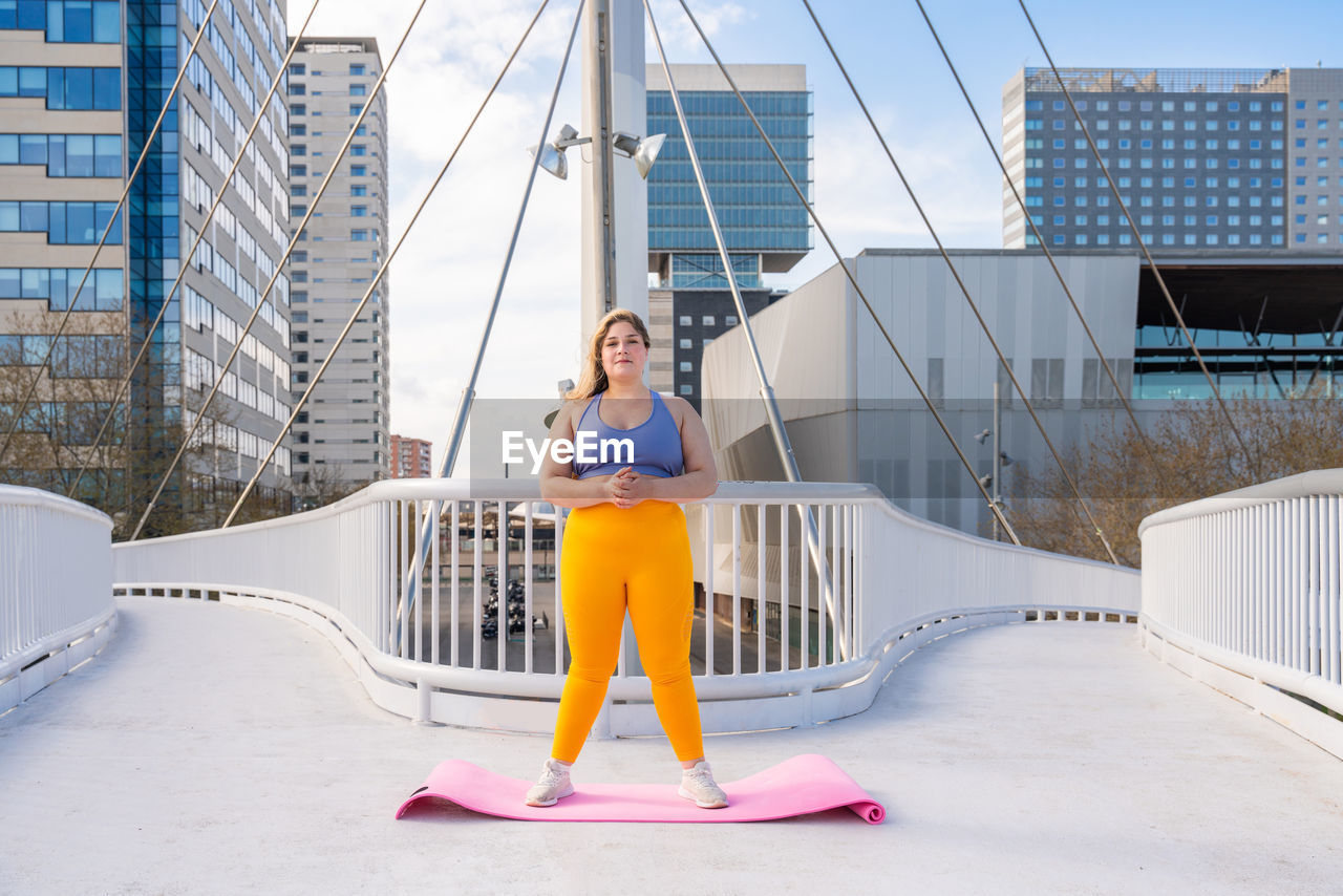 Portrait of young woman standing on footbridge