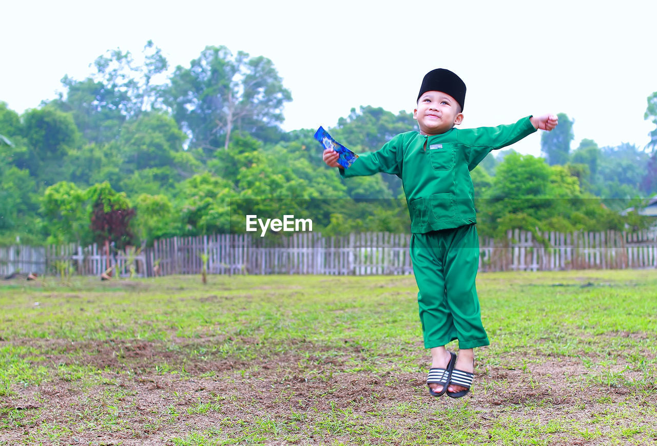 BOY STANDING ON FIELD