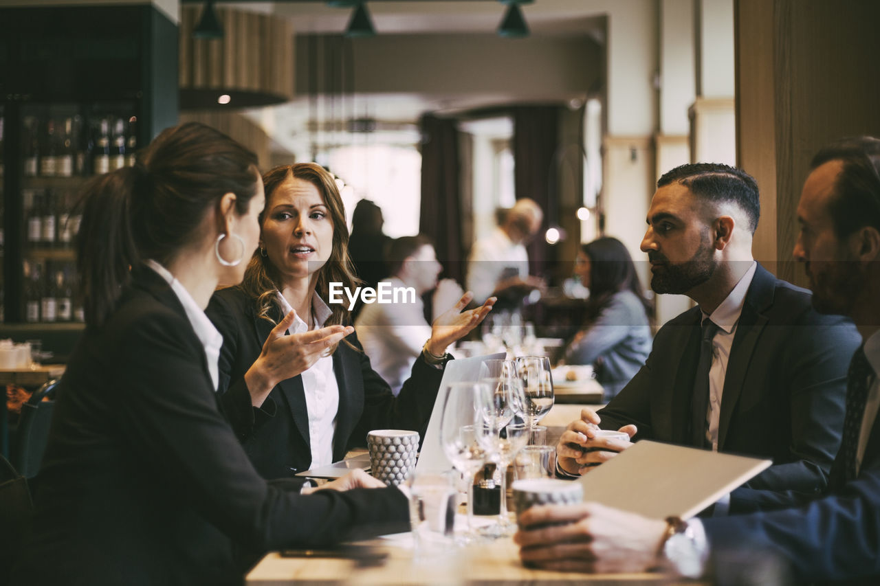 Female entrepreneur discussing with colleagues in restaurant