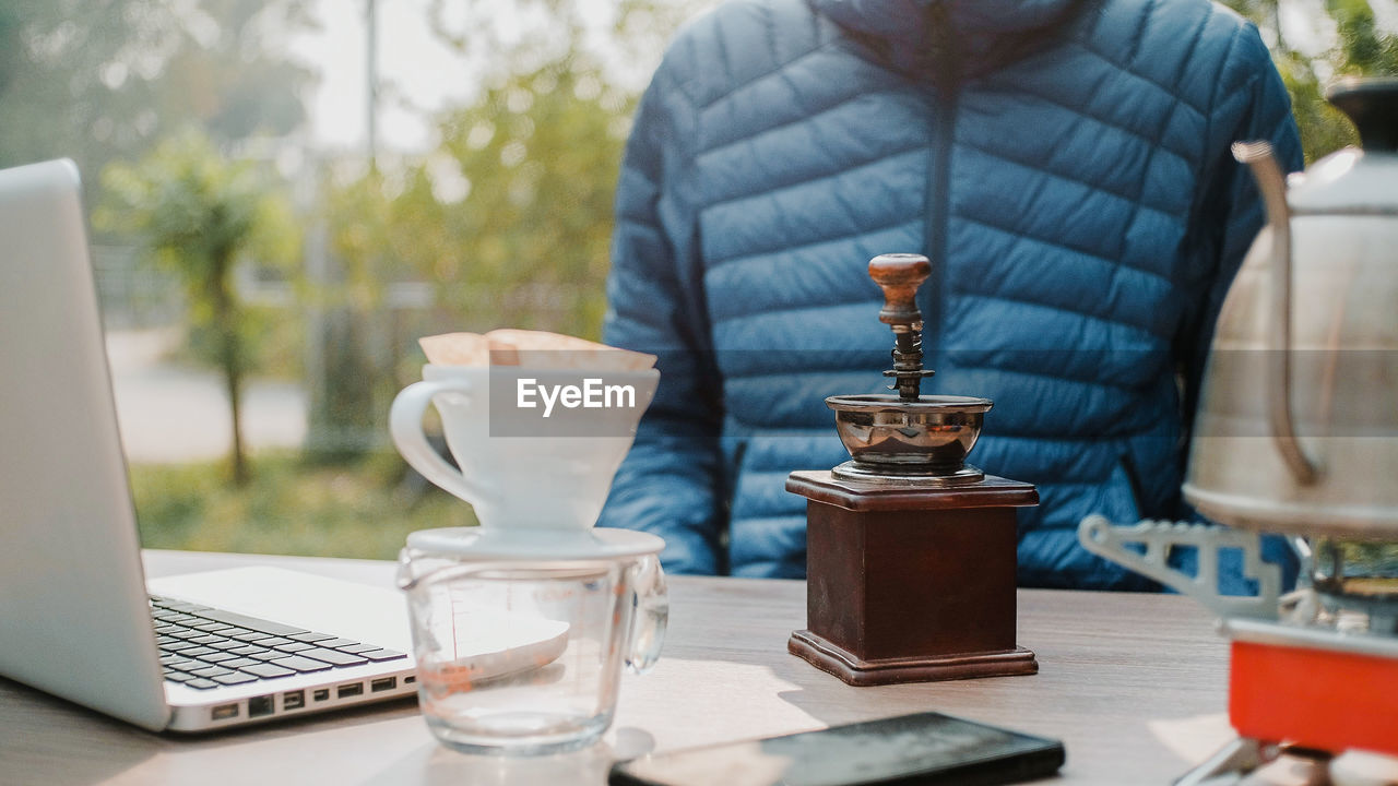 Close up manual coffee grinder for grinding coffee beans on wooden desk in morning.