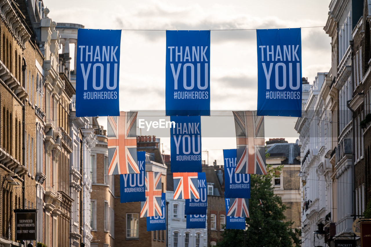 LOW ANGLE VIEW OF FLAG AMIDST BUILDINGS AGAINST SKY