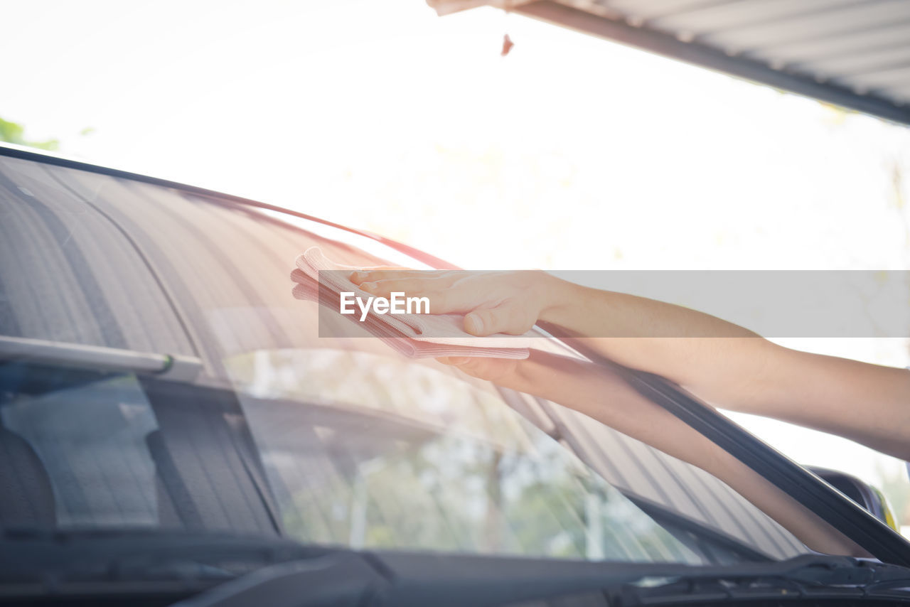 MIDSECTION OF WOMAN READING CAR IN GLASS WINDOW