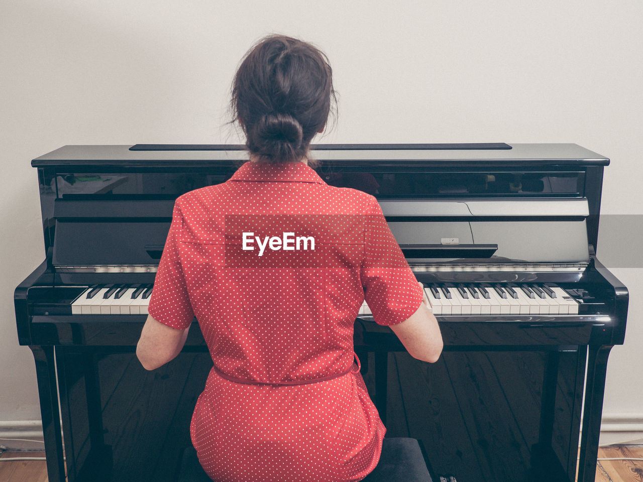 Rear view of woman playing piano at home