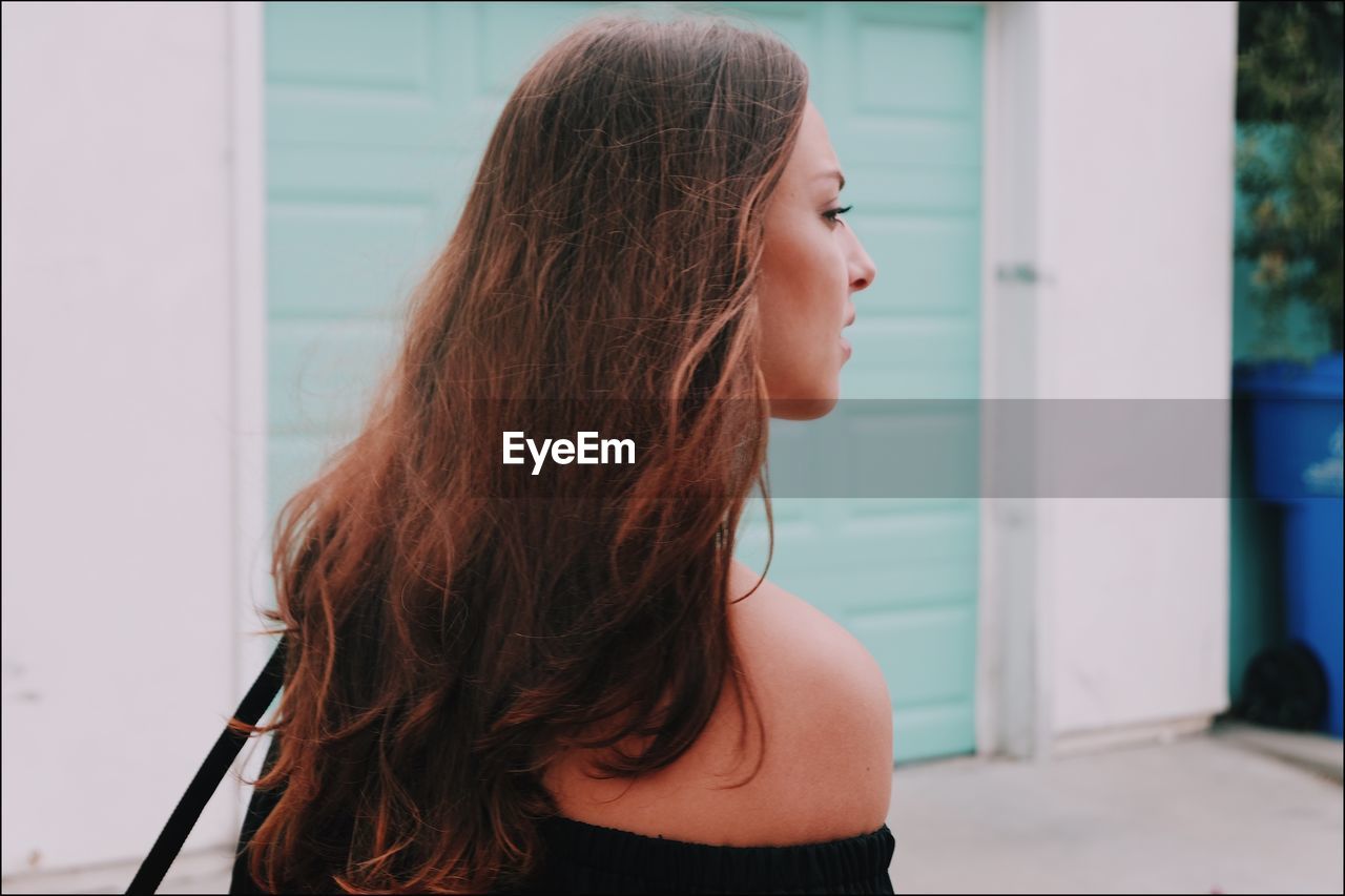 CLOSE-UP OF BEAUTIFUL WOMAN STANDING AGAINST WALL