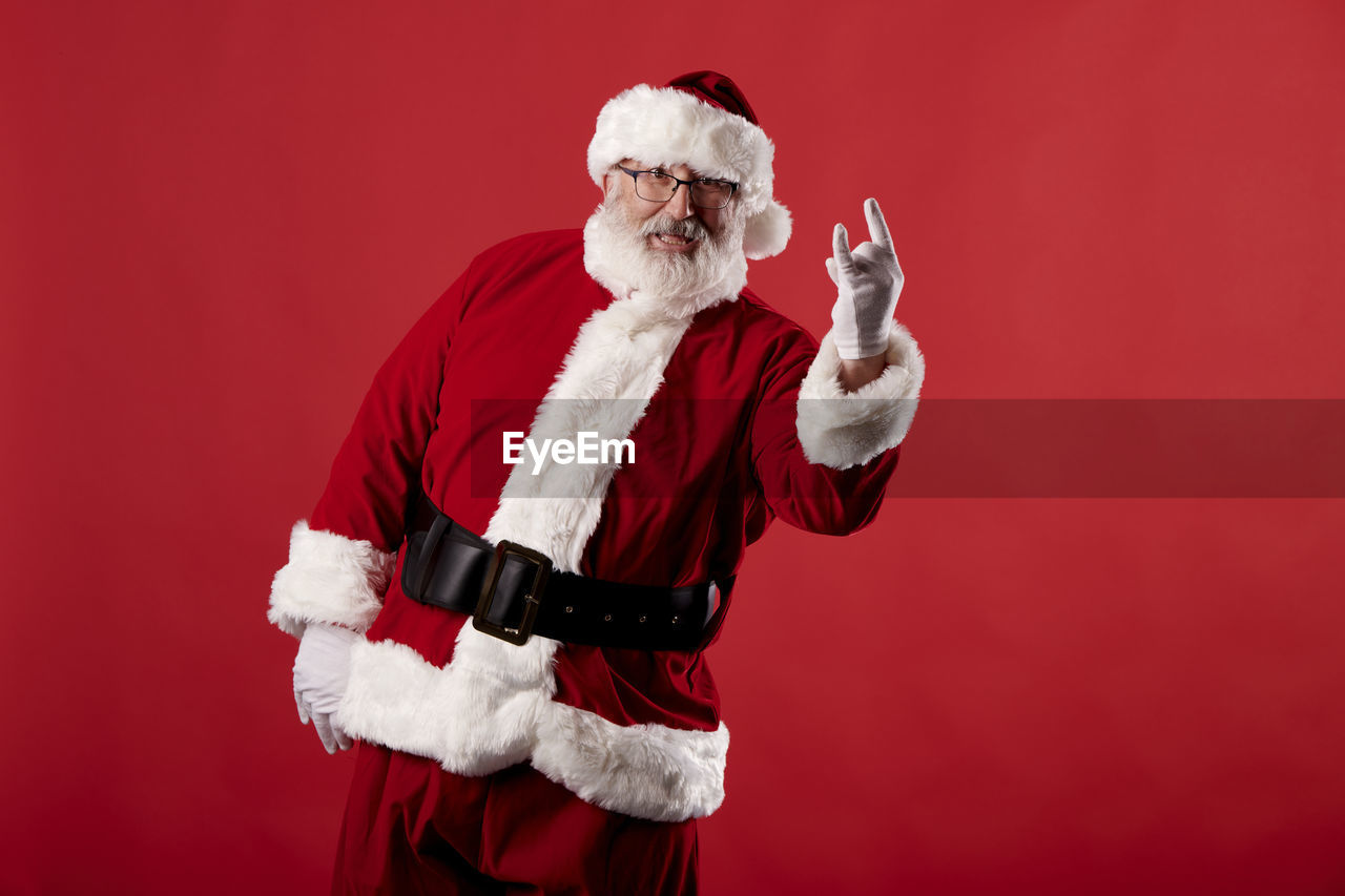 Santa claus making a rocker gesture on a red background